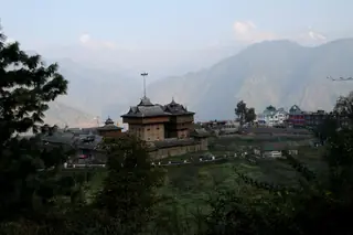 The Bhimakali Temple among trees above the valley, with mountains in the haze beyond
