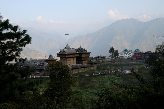 The Bhimakali Temple among trees above the valley, with mountains in the haze beyond