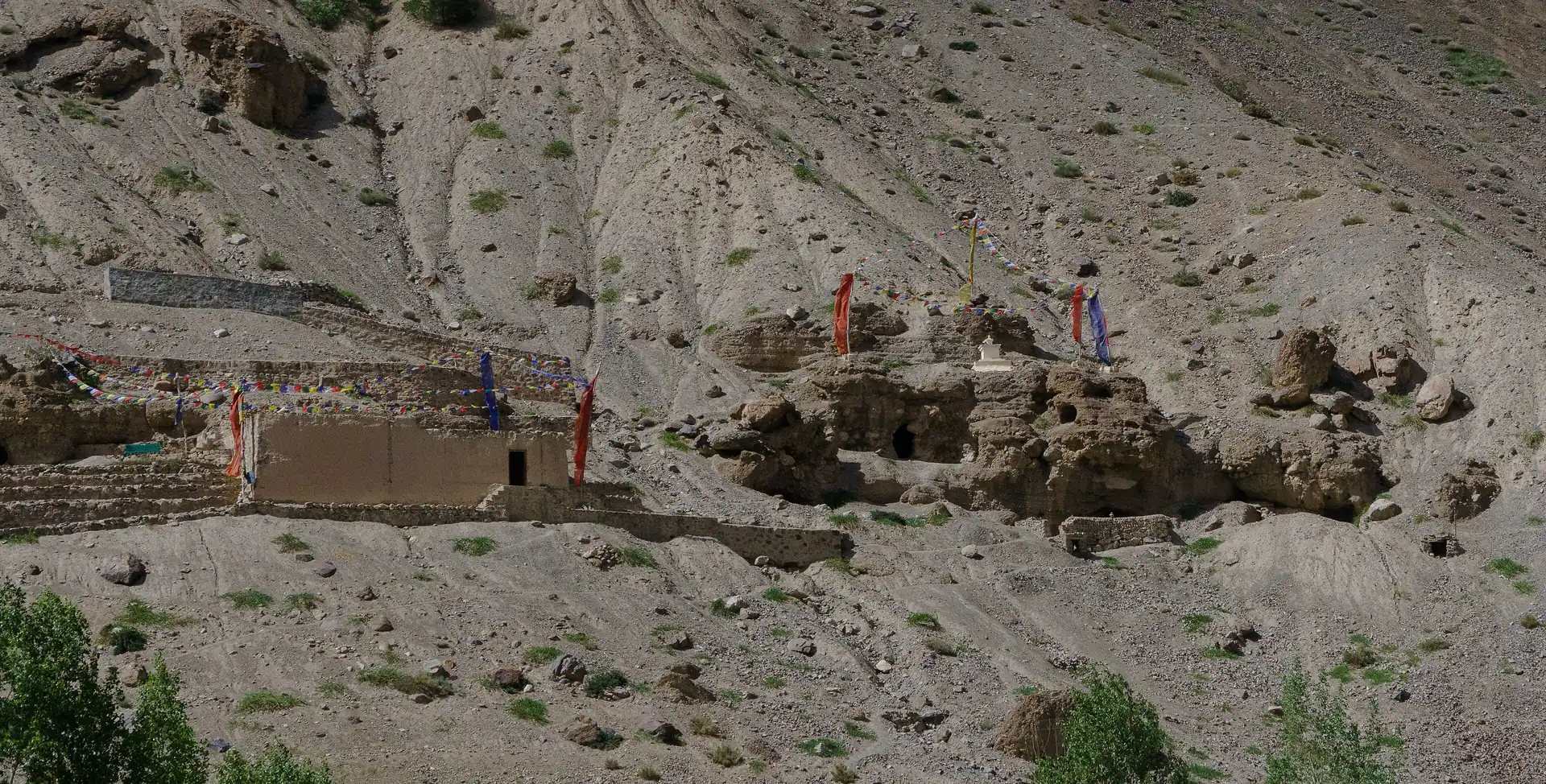 Cave openings cut into the pale cliff above Tabo Monastery