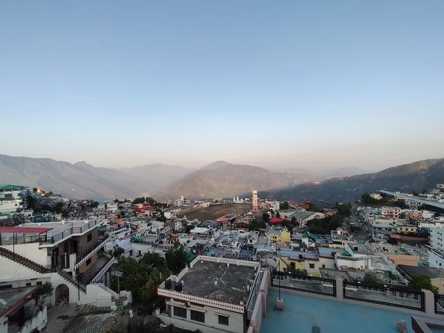 The houses and roofs of New Tehri spread over a hillside with ridges behind in morning light
