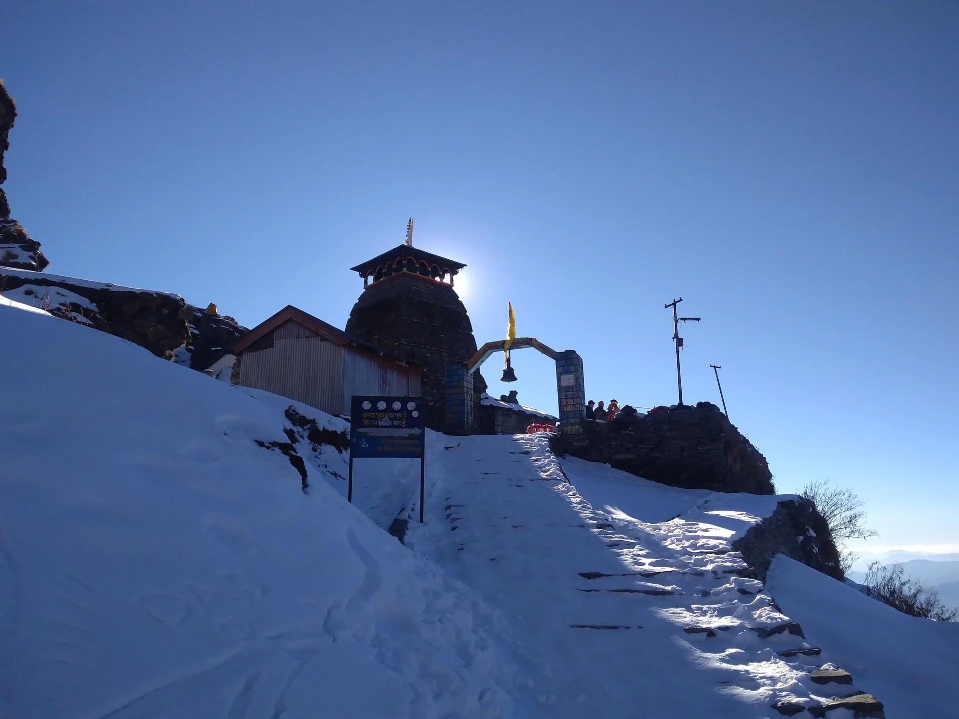 Stone steps buried in snow leading up to the Tungnath Temple under a deep blue sky