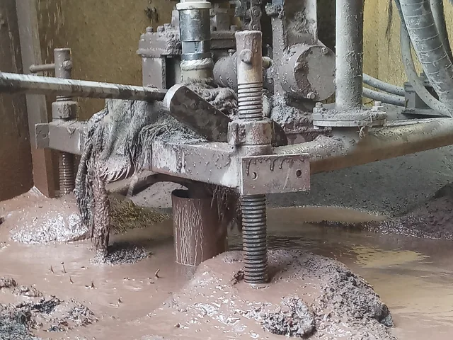 Close-up of the clamp at the foot of the mast, slurry pooling round the drill pipe